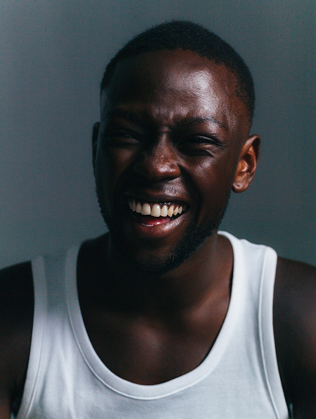 Man wearing a white tank top against a dark background